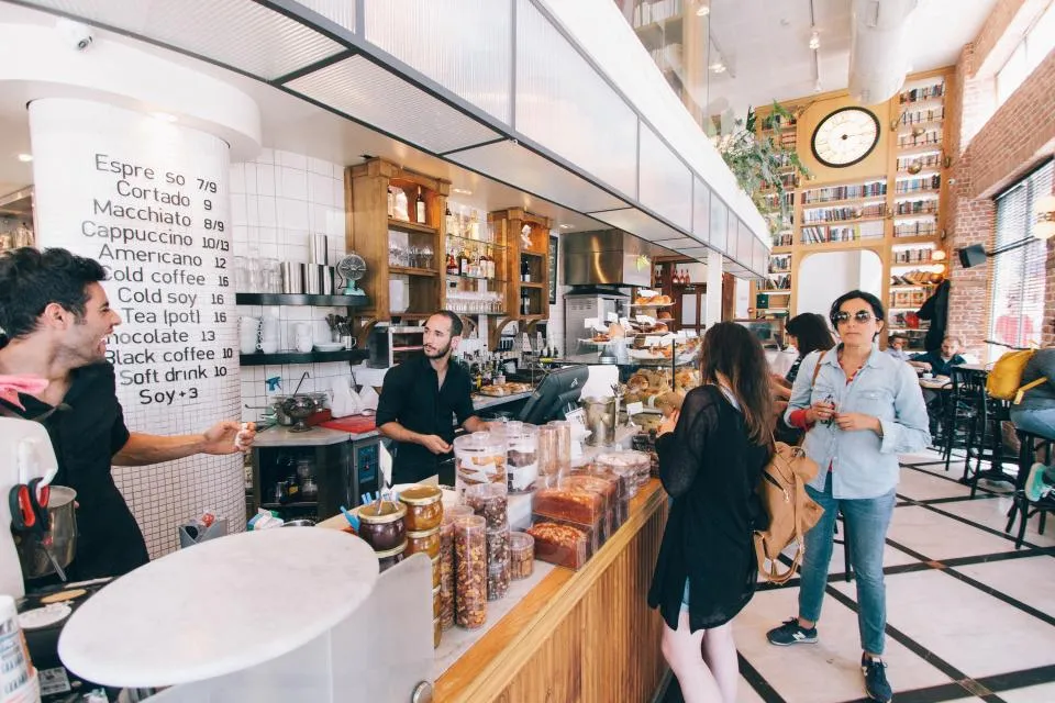 Staff serving customers at the counter of a busy small cafe