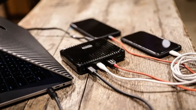 Two smartphones charging from a power bank on a wooden table