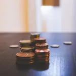 Small stacks of coins on a wooden table, saving a little at a time