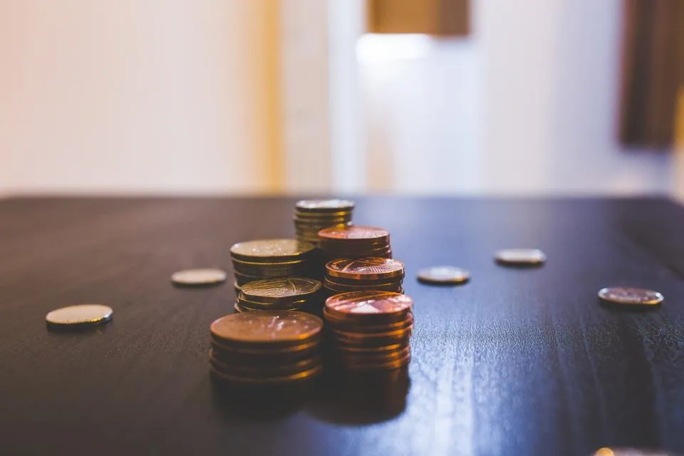 Small stacks of coins on a wooden table, saving a little at a time